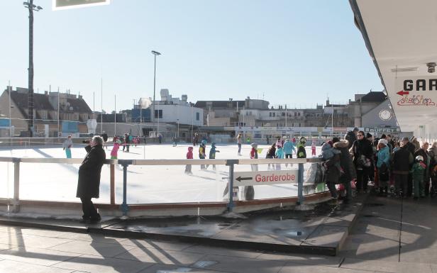 Eine Gruppe von Menschen, darunter viele Kinder, läuft auf einer Eisbahn.