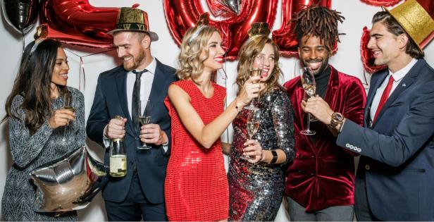 Eine Gruppe von Freunden feiert mit Champagner und Luftballons.