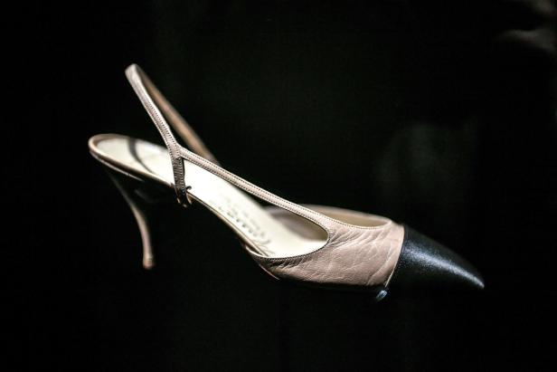 Ein beigefarbener Slingpumps mit schwarzer Spitze vor schwarzem Hintergrund.