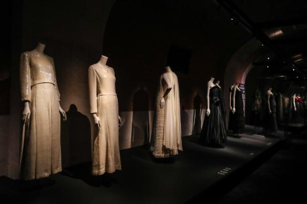 Eine Ausstellung mit eleganten Kleidern auf Schaufensterpuppen in einem abgedunkelten Raum.