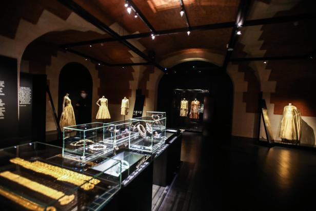 Innenansicht eines Museums mit Schmuck in Vitrinen und Kleidern auf Schaufensterpuppen.