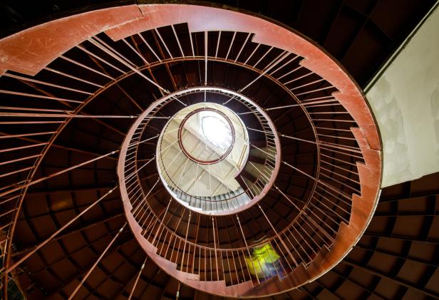 Eine rote Wendeltreppe führt nach oben zu einem hellen Licht.