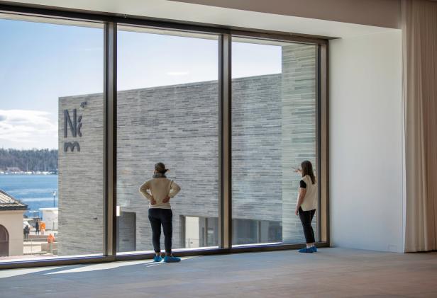 Zwei Frauen betrachten durch ein großes Fenster das Gebäude des Nationalmuseums in Oslo.