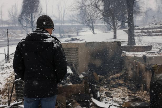 Chris Dreier looks at his house burned by wildfires, in Colorado