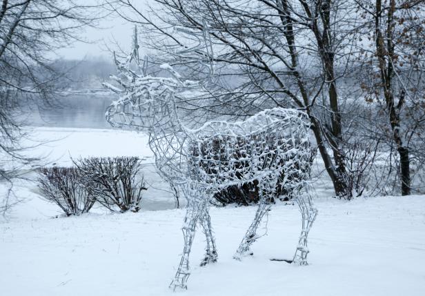 Ein schneebedecktes, drahtgestelltes Rentier steht im Schnee.