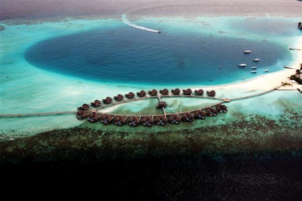 Luftaufnahme eines Resorts mit Wasserbungalows auf einer tropischen Insel.