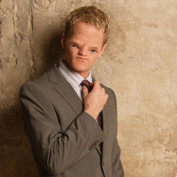 Neil Patrick Harris in einem grauen Anzug vor einer beigen Wand.