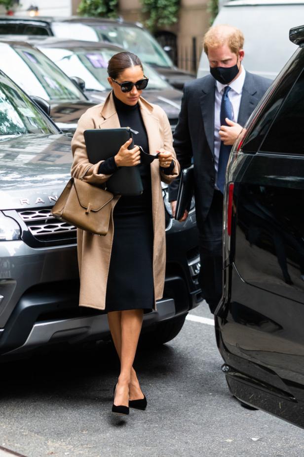 Meghan Markle mit Prinz Harry in New York, gekleidet in einem beigen Mantel und einem schwarzen Kleid.