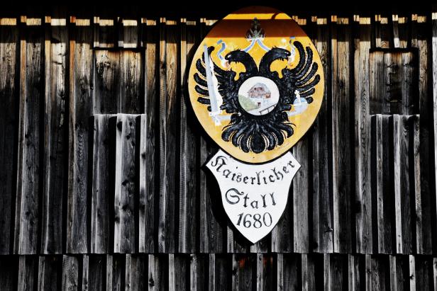 Das Schild „Kaiserlicher Stall 1680“ mit einem Doppeladler hängt an einer Holzwand.