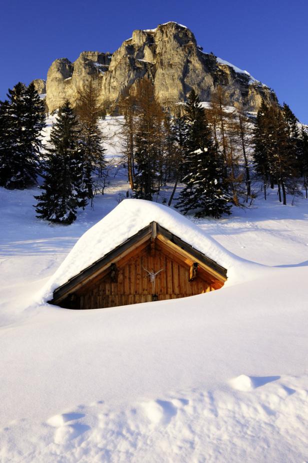 Eine Holzhütte ist im Winter tief im Schnee versunken.