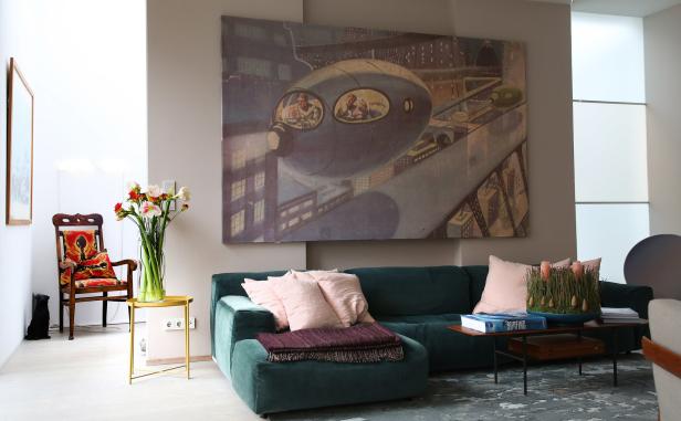 Ein Wohnzimmer mit einem grünen Sofa und einem Gemälde von einem fliegenden Fahrzeug.