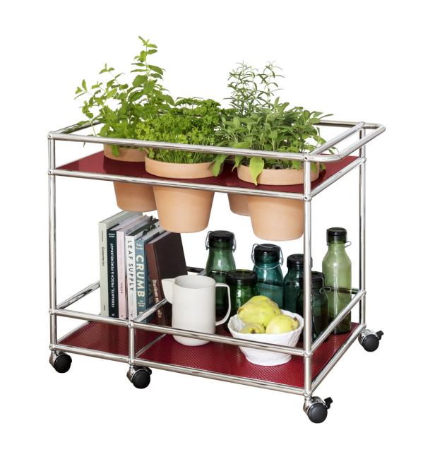 Ein Servierwagen mit Kräutern, Kochbüchern, Gläsern und Obst.