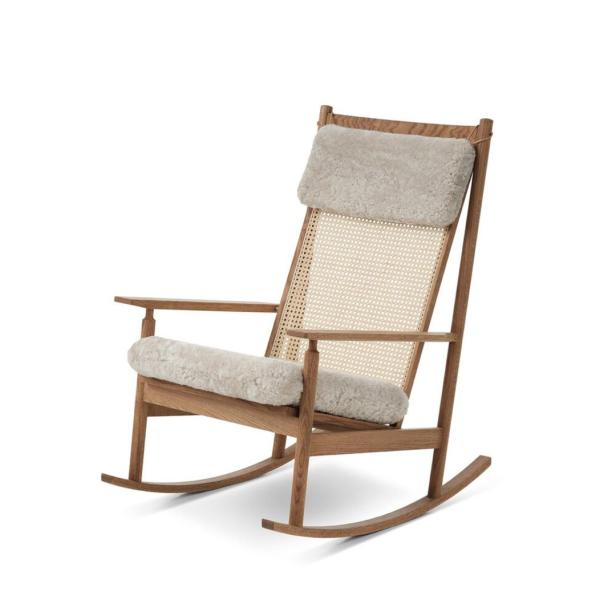 Ein Schaukelstuhl aus Holz mit hellen Polstern und einer Rückenlehne aus Rattan.