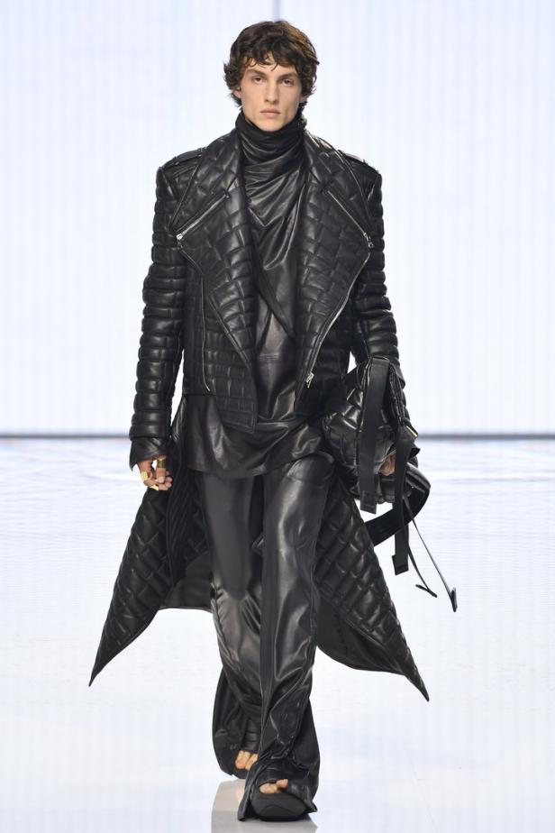 Ein Model in einem komplett schwarzen Lederoutfit auf einem Laufsteg.