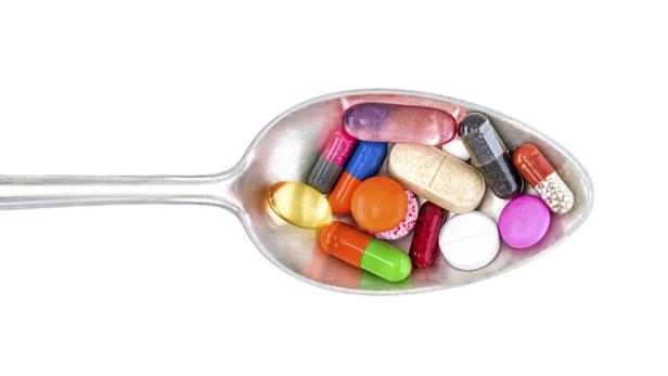 Mehrere Pillen und Antibiotika auf einem Suppenlöffel