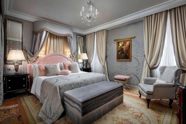 Ein luxuriöses Schlafzimmer mit Himmelbett, Kristalllüster und eleganten Möbeln.