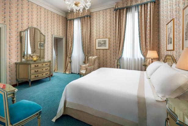 Ein Schlafzimmer mit blauem Teppich, floralen Tapeten und einem großen Bett.