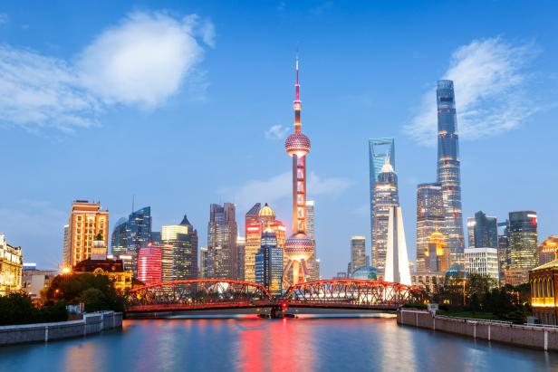 Die Skyline von Shanghai mit dem Oriental Pearl Tower und einer roten Brücke im Vordergrund.
