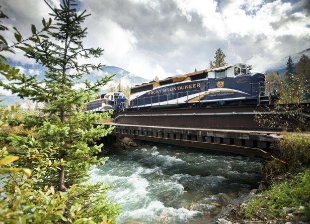 Der „Rocky Mountaineer“-Zug überquert eine Brücke über einen reißenden Fluss.