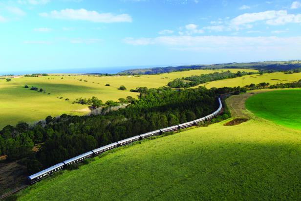 Ein Zug fährt durch eine grüne Landschaft in Küstennähe.