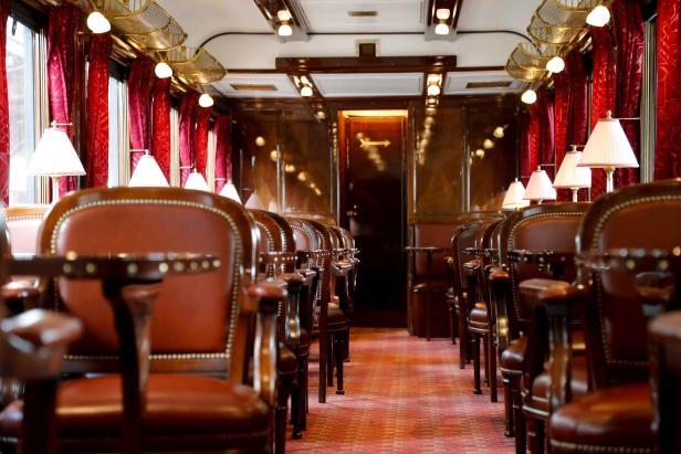Der luxuriöse Salonwagen eines Zuges mit roten Sesseln und Teppich.