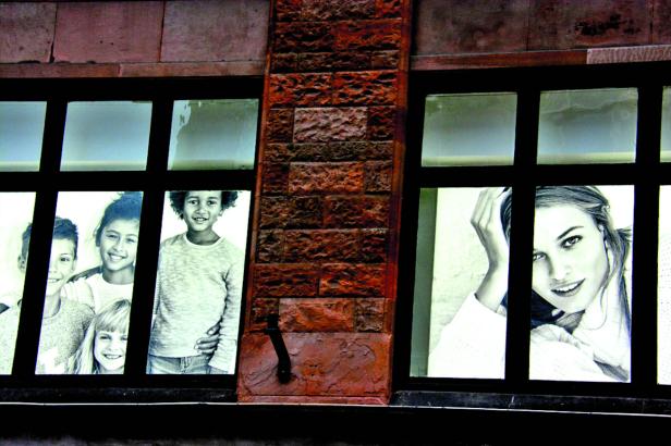 Schaufenster mit Schwarz-Weiß-Porträts von Kindern und einer jungen Frau.