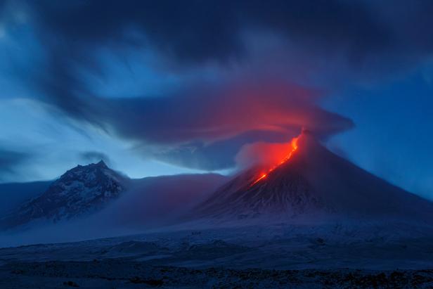 Ein Vulkan bricht nachts aus und speit Lava und Rauch aus.