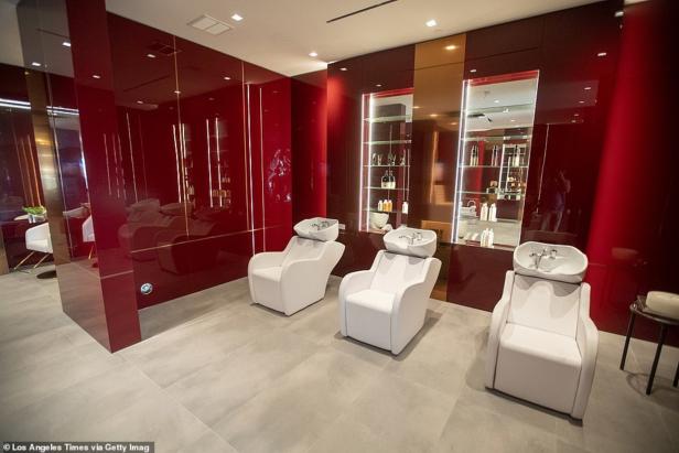 Drei weiße Friseurstühle mit Waschbecken in einem eleganten Salon mit roter Einrichtung.