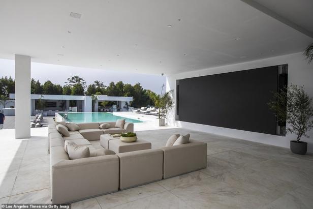 Ein großer, beiger Ecksofa-Bereich mit Blick auf einen Pool und eine Leinwand im Freien.