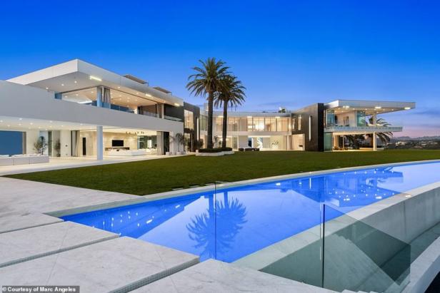 Ein modernes, zweistöckiges Haus mit einem großen Pool im Vordergrund.