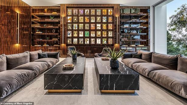Ein luxuriöses Wohnzimmer mit zwei Sofas, Marmortischen und einer Wand mit gerahmten Playboy-Magazinen.