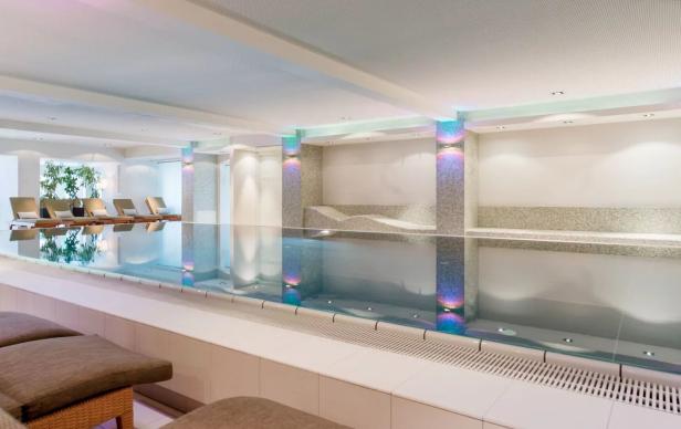 Ein Innenpool mit Liegestühlen in einem Wellnessbereich.