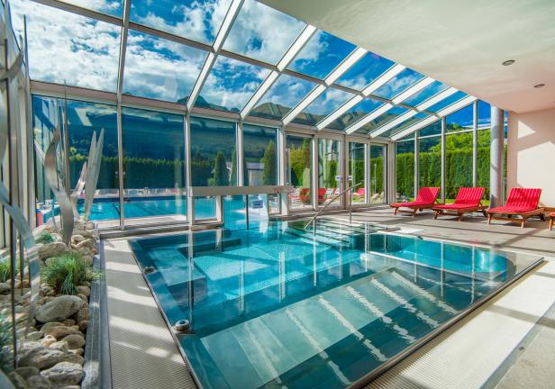 Ein Innenpool mit Glasdach und Blick auf eine grüne Landschaft.