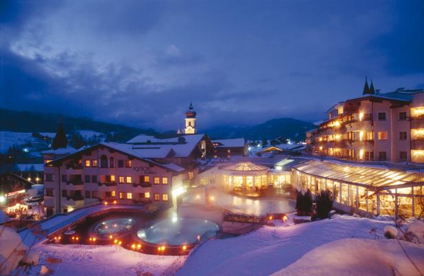 Das Posthotel Achenkirch in winterlicher Nachtansicht mit beleuchteten Pools und Gebäuden.