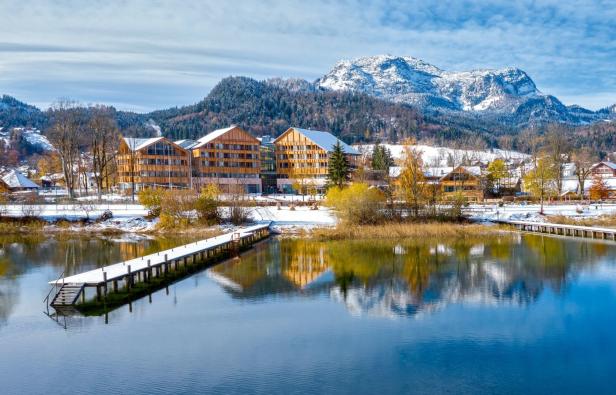 Ein Hotel am Ufer eines Sees mit schneebedeckten Bergen im Hintergrund.