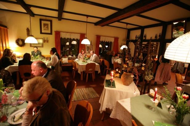 Mehrere Personen sitzen an Tischen in einem warm beleuchteten Restaurant.