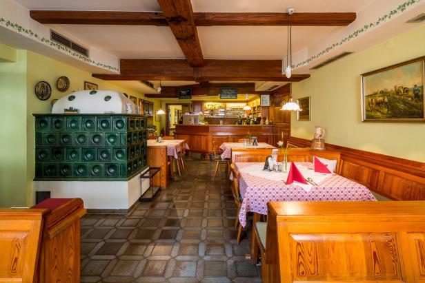 Innenansicht eines traditionellen deutschen Restaurants mit Kachelofen und Holzbalken.