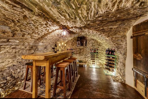 Ein Weinkeller mit Steingewölbe, Holztisch und Weinregalen.