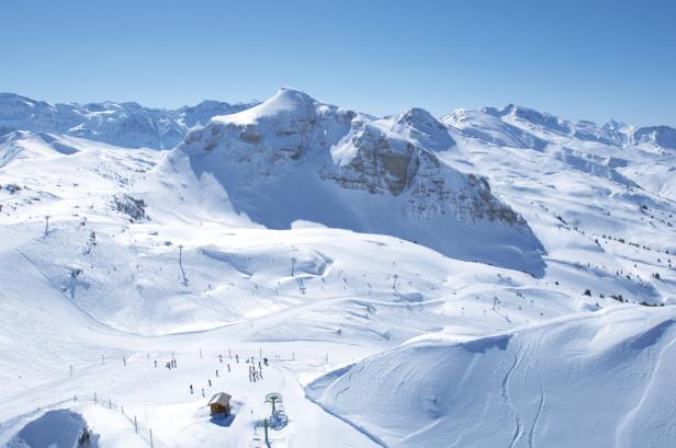 Eine verschneite Berglandschaft mit Skipisten an einem sonnigen Tag.