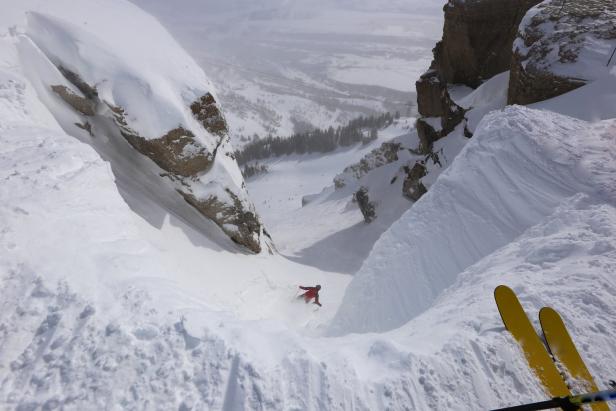 Ein Skifahrer fährt eine steile, schneebedeckte Rinne hinunter.