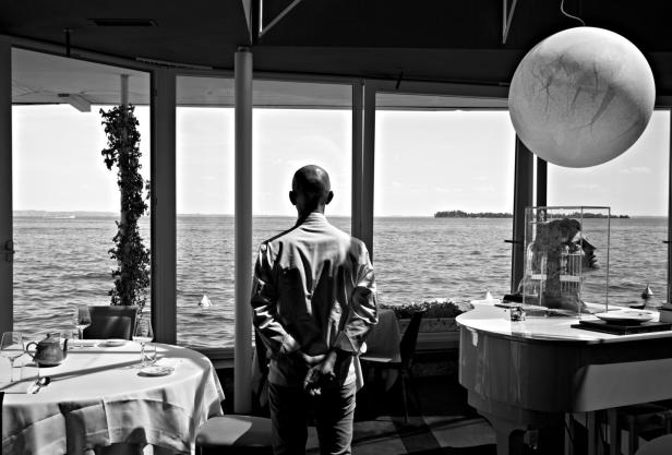 Ein Mann steht in einem Restaurant und blickt auf das Meer.
