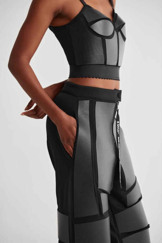 Eine Frau trägt ein zweiteiliges Outfit mit geometrischen Formen in Schwarz und Grau.