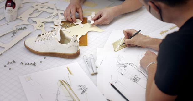 Ein Designer arbeitet an Skizzen und Prototypen für einen Adidas Stan Smith Schuh.