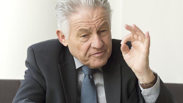 Ein älterer Mann im Anzug gestikuliert mit der Hand, um Zustimmung auszudrücken.