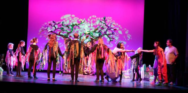 Eine Gruppe von Kindern führt ein Theaterstück auf einer Bühne auf.
