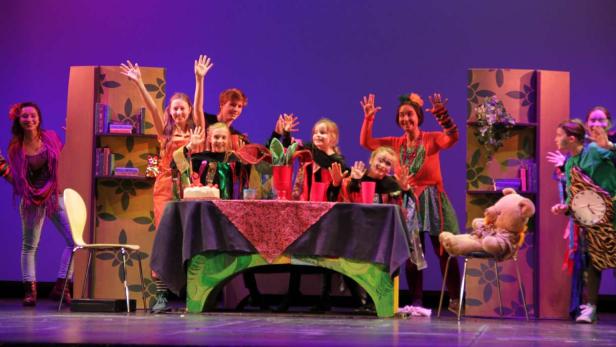 Eine Gruppe von Kindern und Erwachsenen auf einer Bühne während einer Theateraufführung.