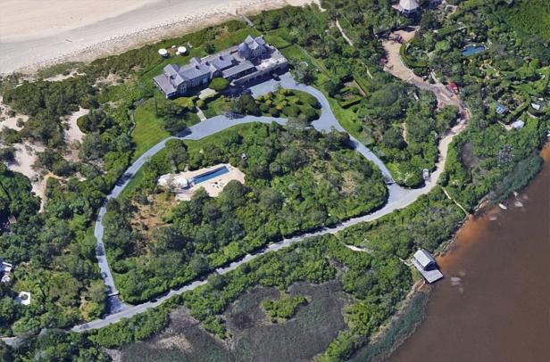Luftaufnahme eines großen Hauses mit Pool und gepflegten Gärten in Küstennähe.
