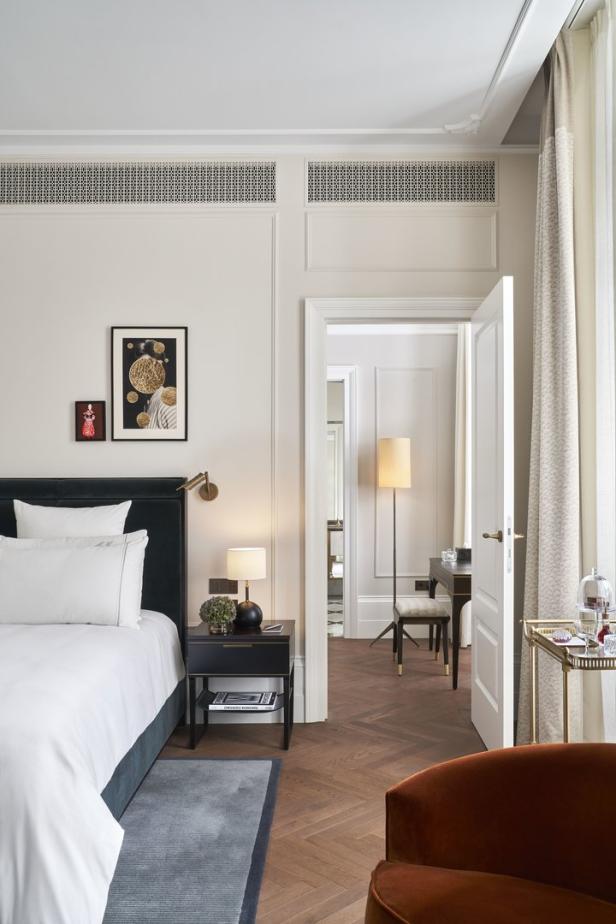 Ein Schlafzimmer mit einem Bett, einem Nachttisch und einem Blick in ein angrenzendes Zimmer.