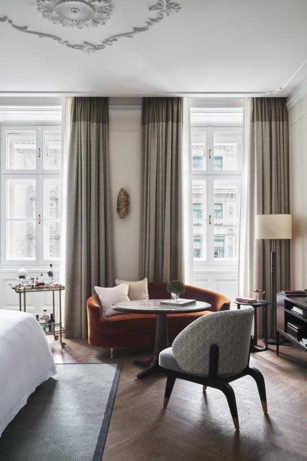 Ein Hotelzimmer mit einem Sofa, einem Tisch und einem Stuhl vor einem Fenster.