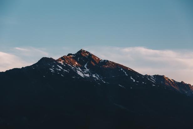 Ein Berg mit etwas Schnee unter einem blauen Himmel.